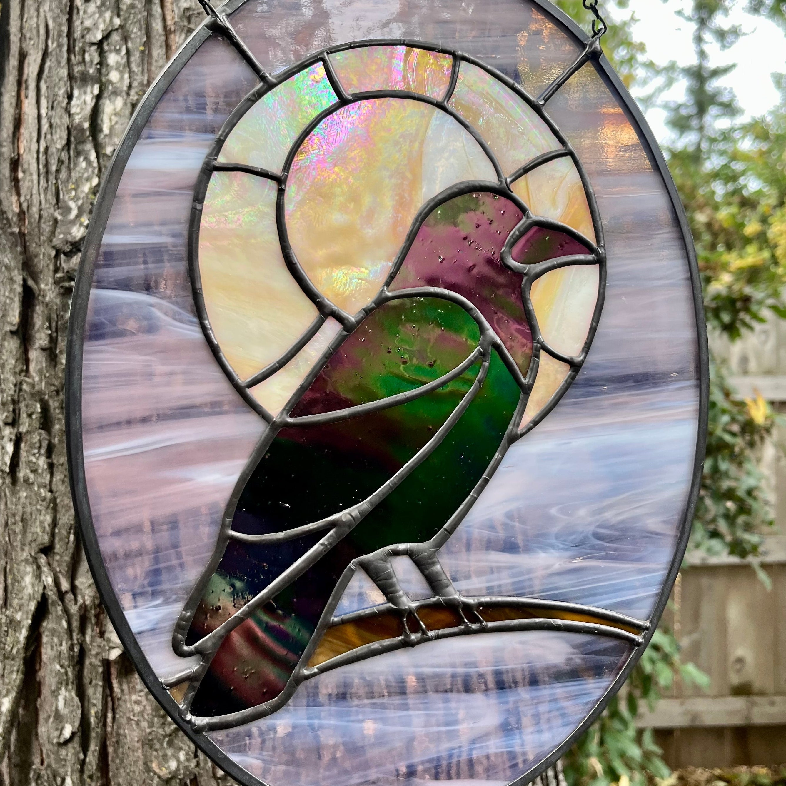 Stained glass bird panel hanging on a tree